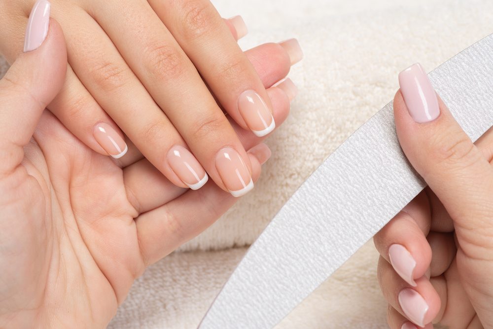 Woman gets manicure procedure in a spa salon. Beautiful female hands. Hand care. Woman cares for the nails on hands. Beauty treatment with skin of hand.   Woman's hands close-up view.